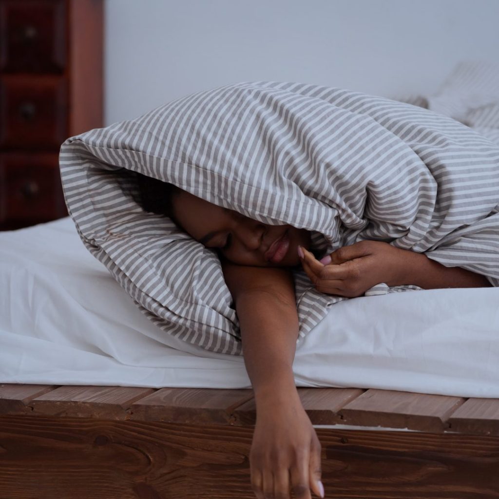A lady sleeping under a gray and white striped blanket.